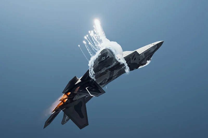 Hızı Fotoğrafa Dönüştürmek: Simone Marulli’nin Uçak Kareleri 25 Bir F-22 Raptor, açık mavi gökyüzünde manevra yaparken parlak flare'ler bırakıyor.