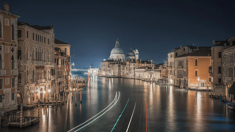 Hızı Fotoğrafa Dönüştürmek: Simone Marulli’nin Uçak Kareleri 36 Venedik Grand Canal'ın uzun pozlama gece görüntüsü; geçen teknelerin ışık izleri ve uzakta aydınlatılmış Basilica di Santa Maria della Salute görülüyor.