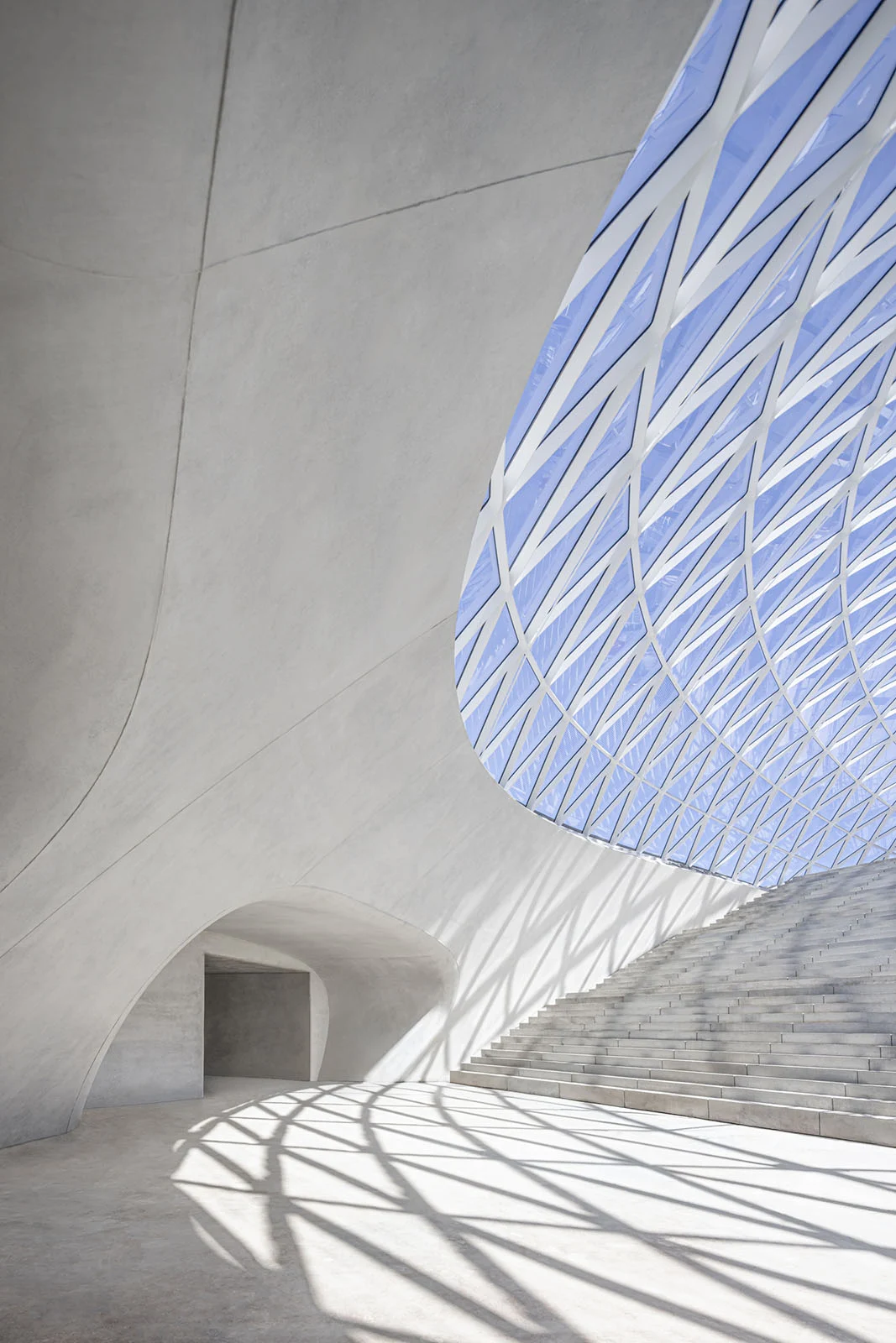 Architecture Photography MasterPrize 2026 Kazananları Açıklandı 27 Geniş ve kıvrımlı beton yapı, geometrik ızgara desenli büyük tavan açıklığıyla merdivenlere ve düzgün zemine gölgeler düşürüyor.