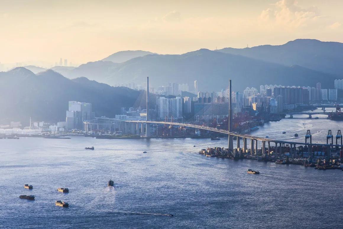 Architecture Photography MasterPrize 2026 Kazananları Açıklandı 28 Kablo askılı köprü, yük gemileriyle dolu geniş limanın üzerinden uzanırken arka planda yoğun kent dokusu ve dağlar gün batımında görülüyor.