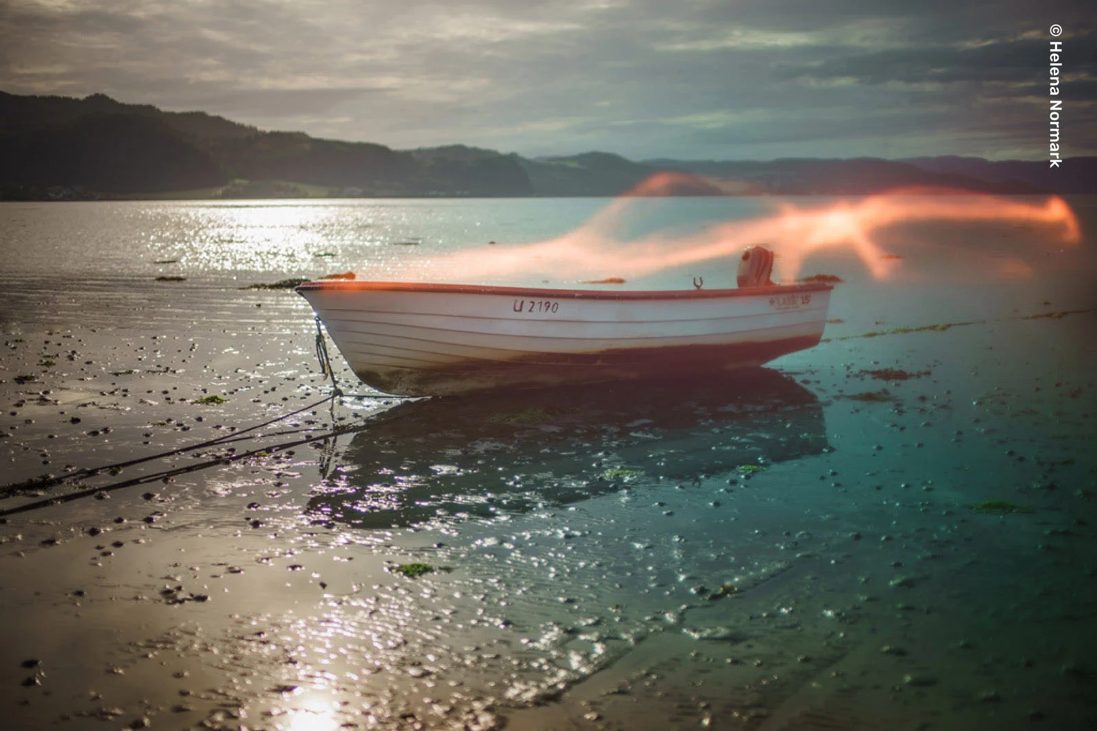Lensbaby Omni Color II ve Omni Crystal II ile Çekim Sırasında Yaratıcı Efektler 22 A small white boat with the registration number U 2190 sits on a muddy shoreline at low tide, with a glowing light trail above it.