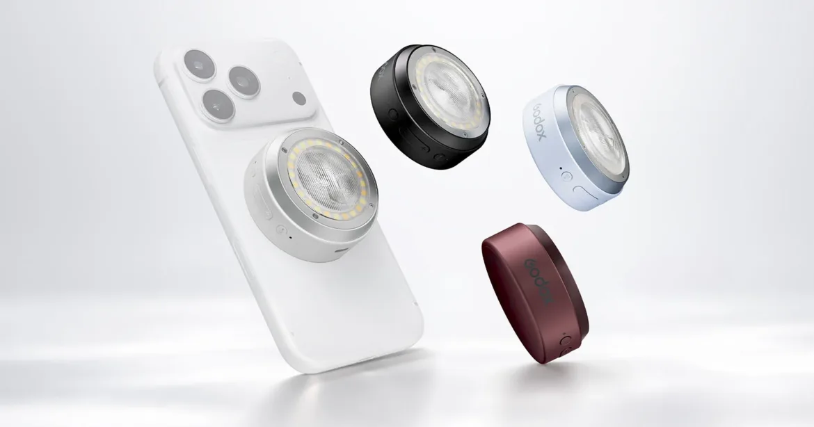 A white smartphone with a circular magnetic light attached to its back, surrounded by three additional lights in black, light blue, and dark red.