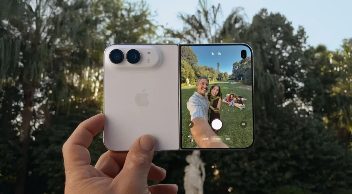 Apple iPhone Duo: İlk Katlanabilir iPhone 7,6 İnç Ekranla Geldi 31 Bir el beyaz katlanabilir akıllı telefonu tutuyor; ekrandaki kamera arayüzünde parkta selfie çeken bir kadın ve erkek görülüyor.