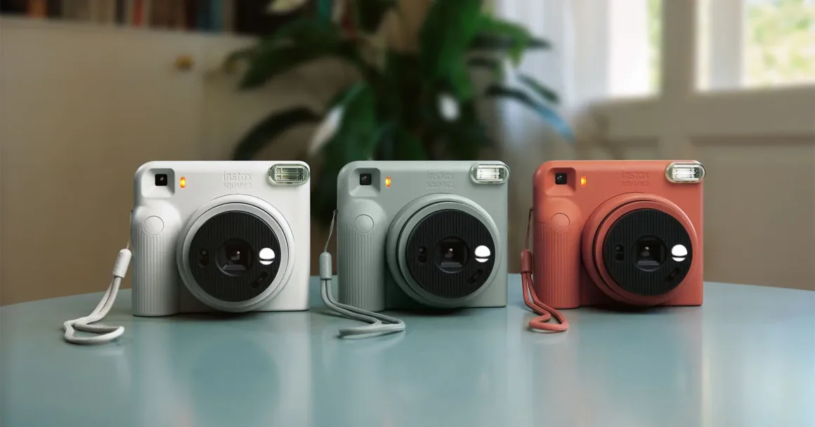 Fujifilm Instax Square 2: Yeni Tasarım, Yeni Mood Filtreleri 23 Beyaz, adaçayı yeşili ve terracotta turuncu renklerde üç Instax Square 2 anlık fotoğraf makinesi açık mavi bir masa üzerinde yan yana duruyor.