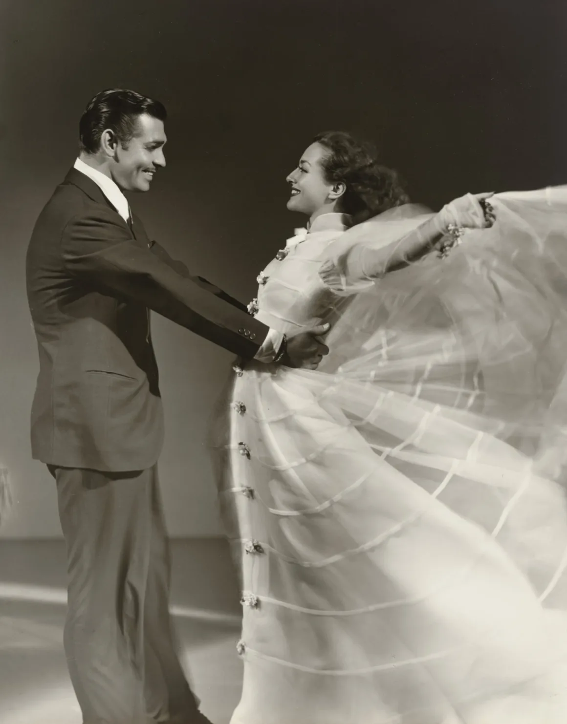 Hollywood’un Altın Çağındaki Glamoru Fotoğraflayan Adam: George Hurrell 20 Clark Gable ve Joan Crawford birlikte dans ediyor; Crawford yana doğru savrulan beyaz ve dökümlü bir elbise giyiyor.