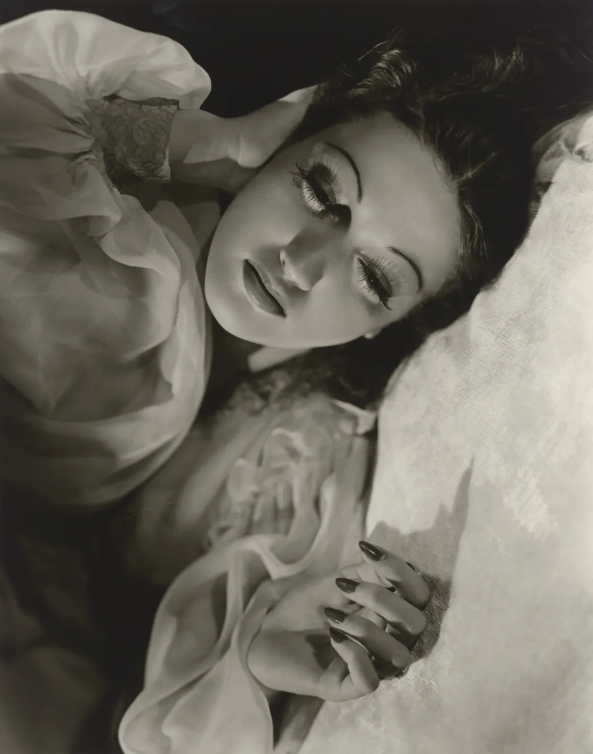 Hollywood’un Altın Çağındaki Glamoru Fotoğraflayan Adam: George Hurrell 19 Uzun kirpikli bir kadın, başını eline yaslayarak uzanmış hâlde siyah-beyaz portre için poz veriyor.