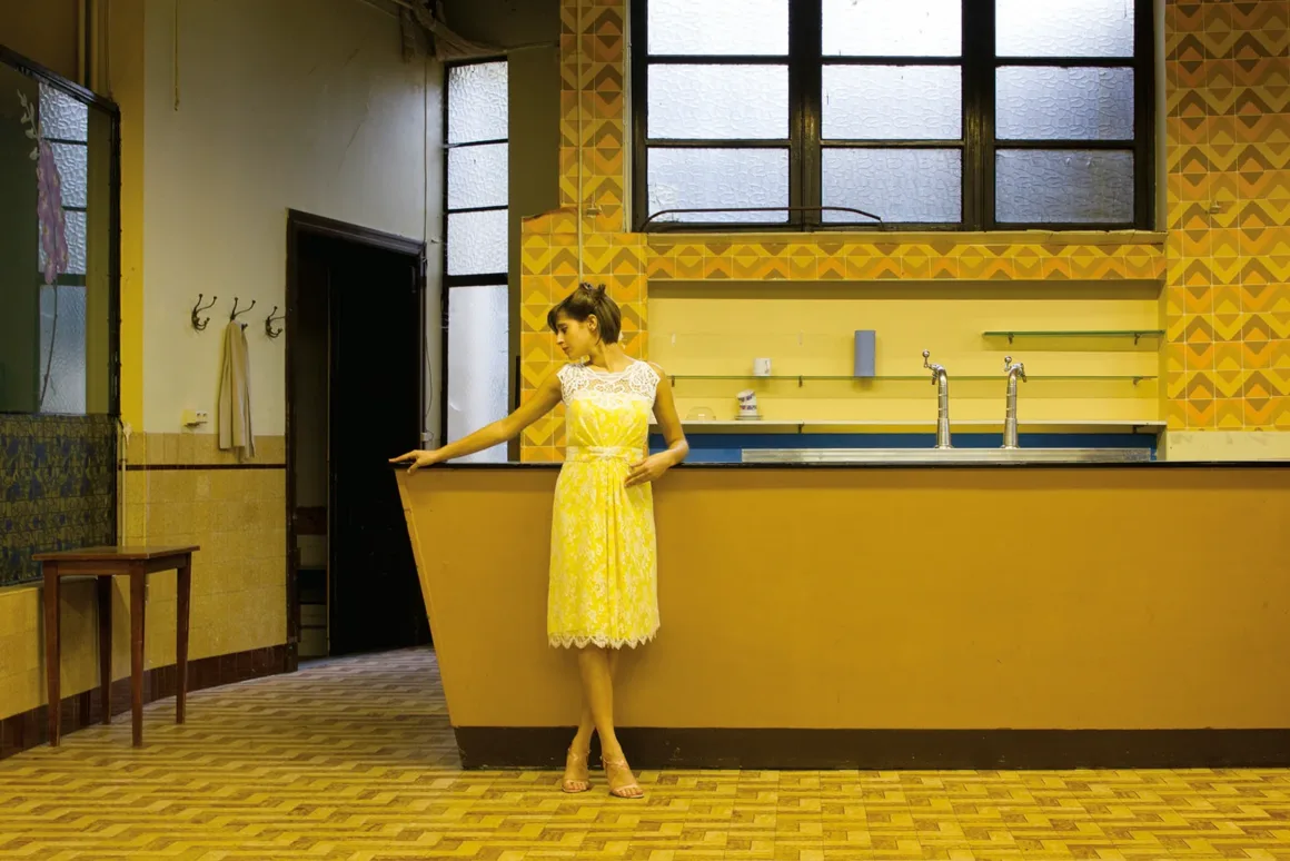 Sarı Rengin 100 Yorumu: The Colour Library: Yellow
Sarı dantel elbise giyen bir kadın, sarı desenli duvarlar ve karo zeminlerle çevrili bir mekânda bar tezgâhına yaslanıyor.