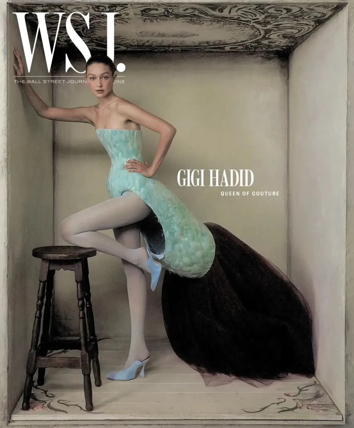 Vogue, Elle ve WSJ’nin Benzer Kapakları Tartışma Yarattı 21 Gigi Hadid, açık mavi tüylü ve yapısal bir elbiseyle duvara yaslanırken yanında ahşap bir tabure bulunuyor.